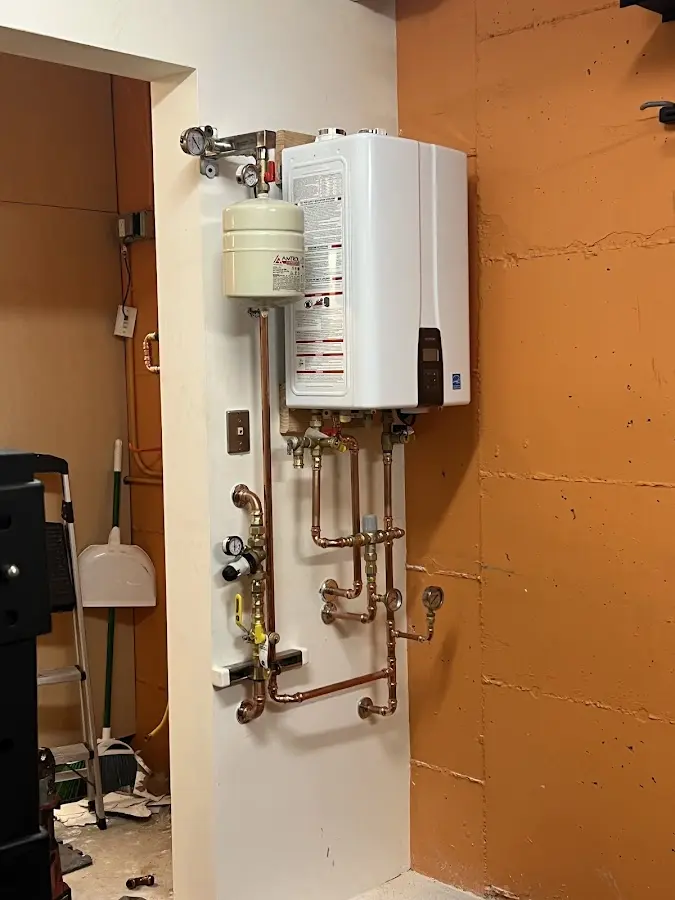 Plumbing technician inspecting water heater connections in Purcell